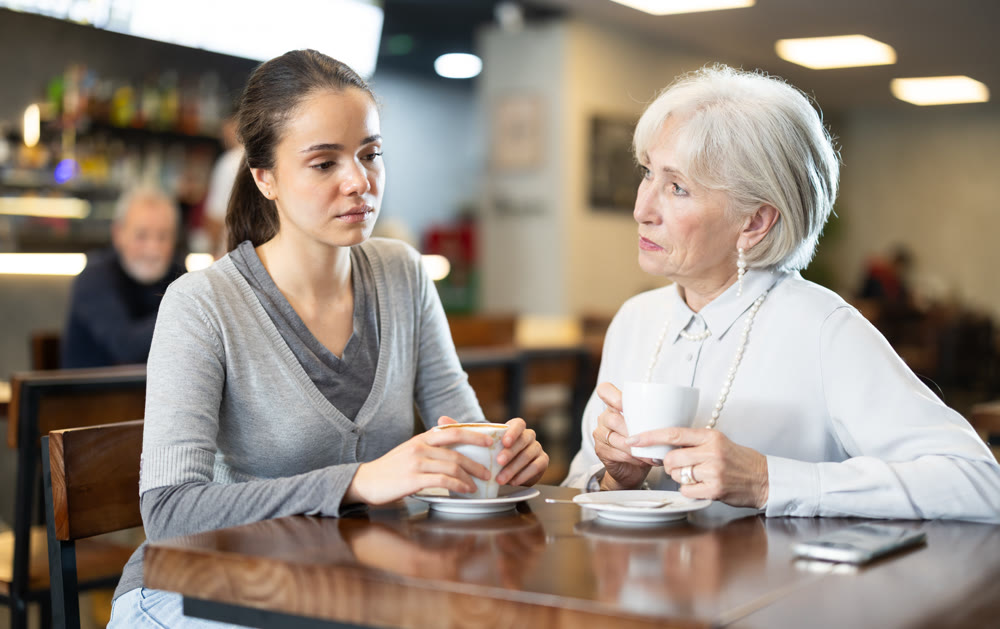 Young and elderly woman drinking coffee in cafe