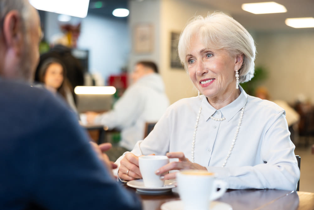 Senior spouses in cafe, chat and joke, flirting, eat and drink coffee