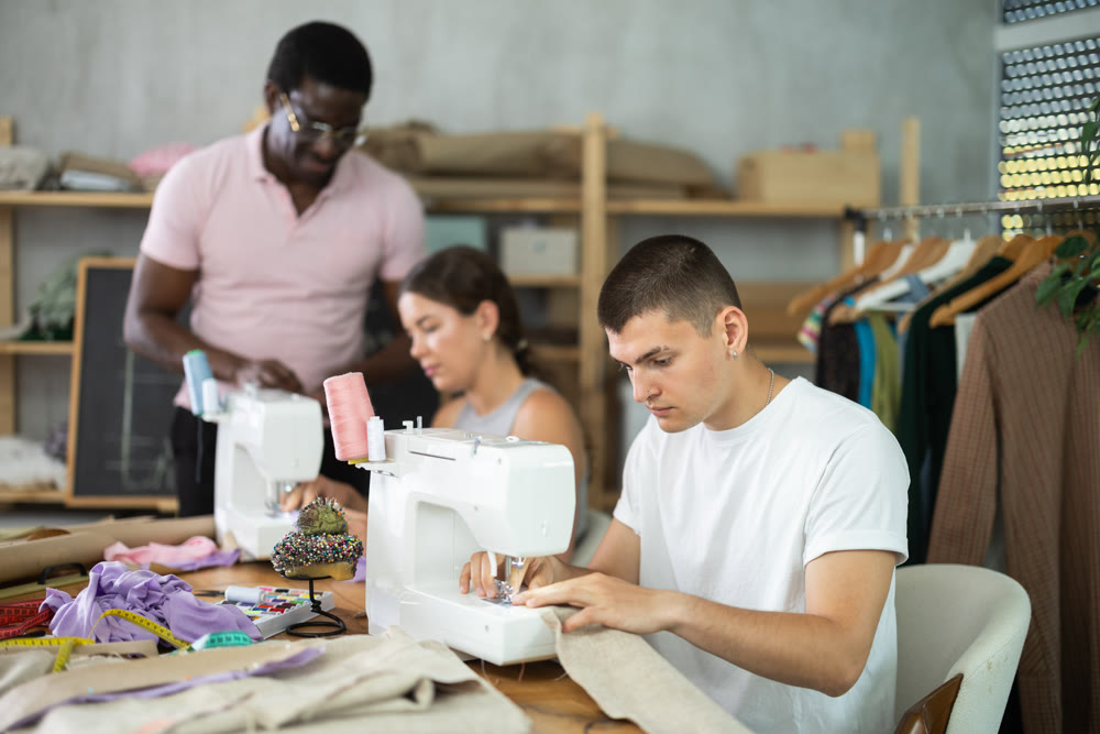 Interested guy working at machine during group sewing course for adults
