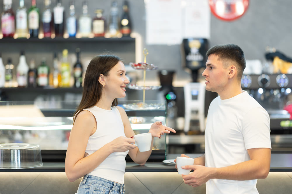 Young couple talking and drinking coffee in cafe