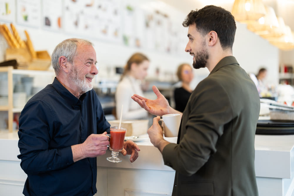 Senior man with guy meeting at cafe for cup of coffee