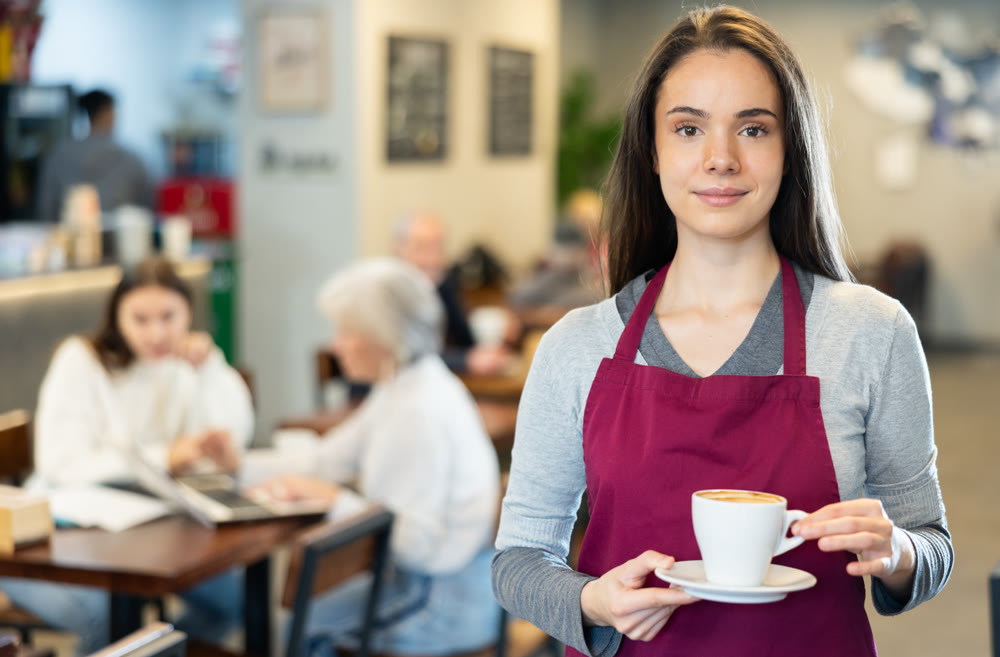 Young woman barista holding coffee