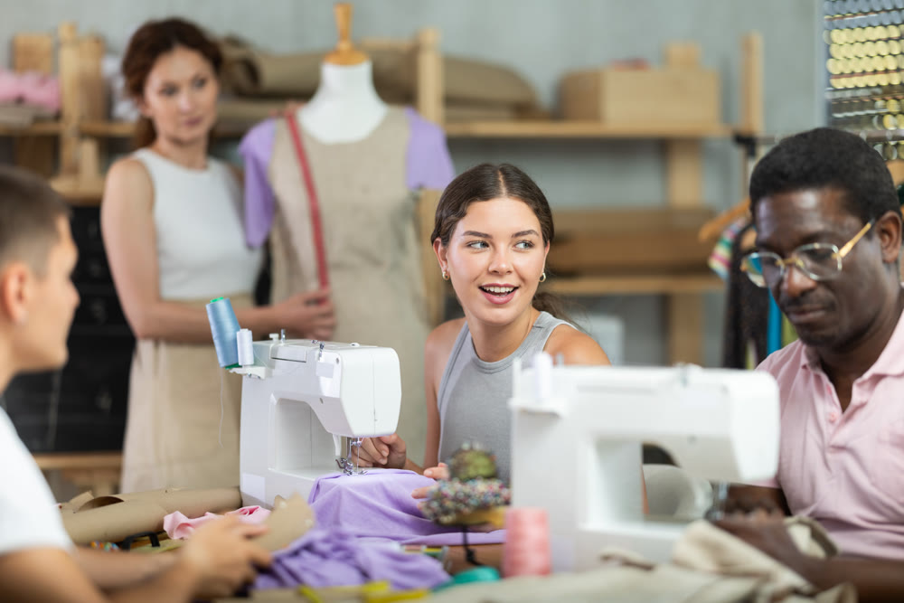 Young woman stitching at machine during sewing class for adults