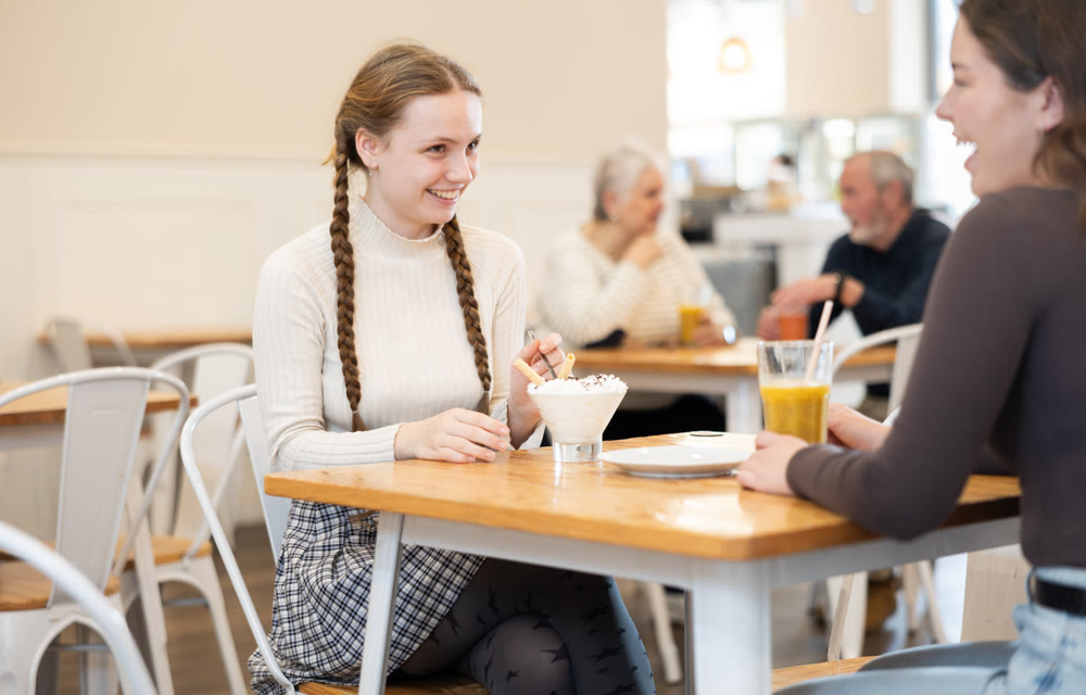 Young woman chatting with teenager in cafe