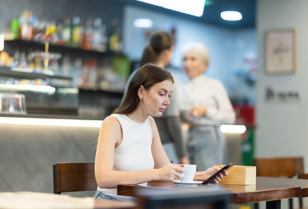 Young woman sitting in cafe and chatting on mobile phone