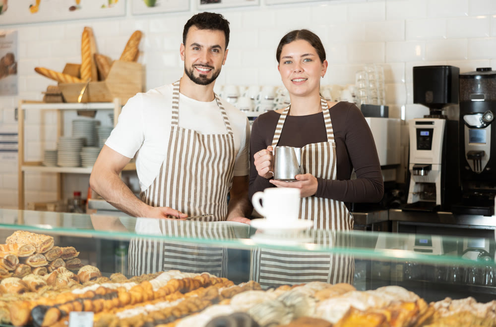 Two cafe employees preparing coffee and delicious pastries