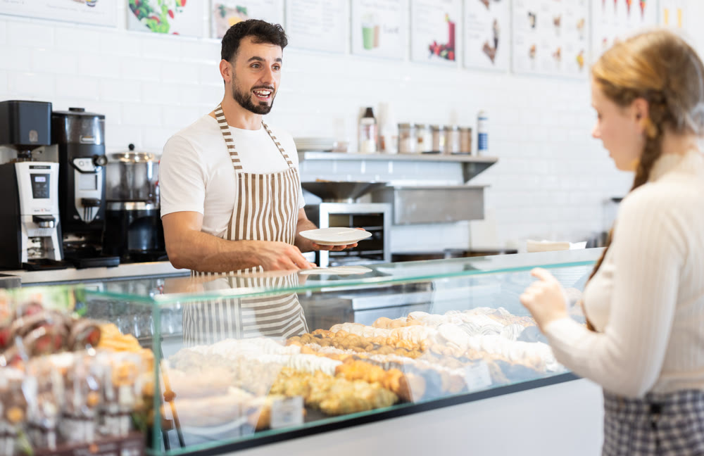 man coffee shop worker offers fresh pastries to customers