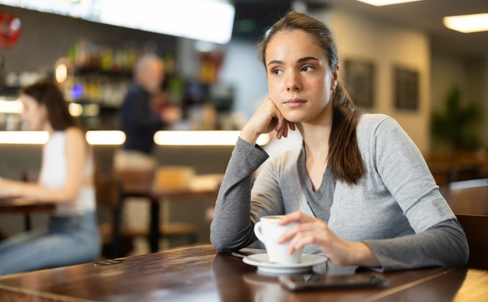 Girl whiles away time and drink coffee in cafe