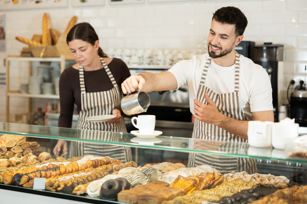 Two cafe workers prepare coffee for a customer