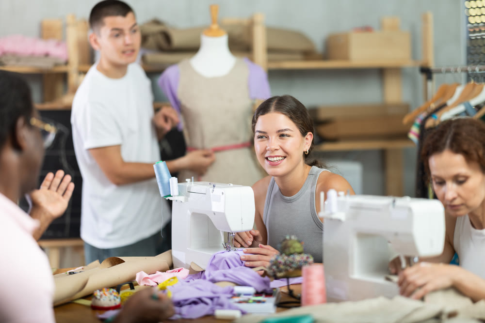Young girl talking and sewing, other working with mannequin