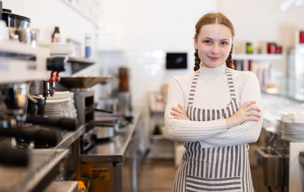 Coffee shop intern prepares coffee for customers.