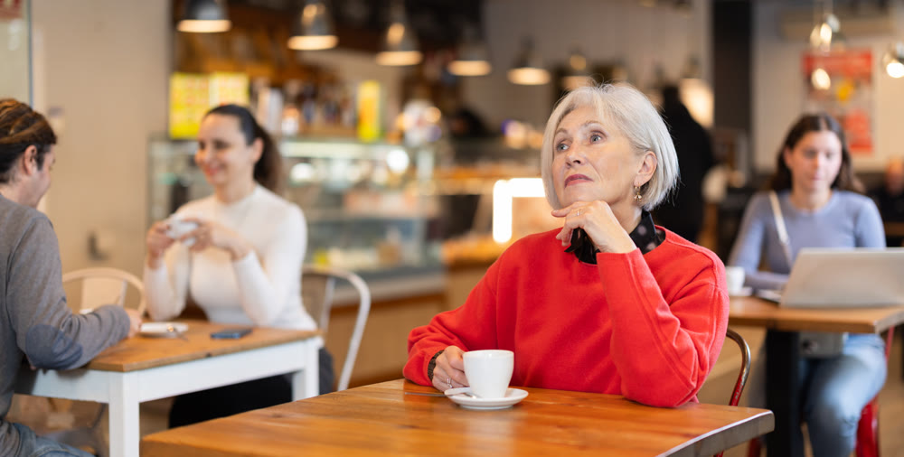 Senior woman whiles away time and waits for meeting in chain cafe