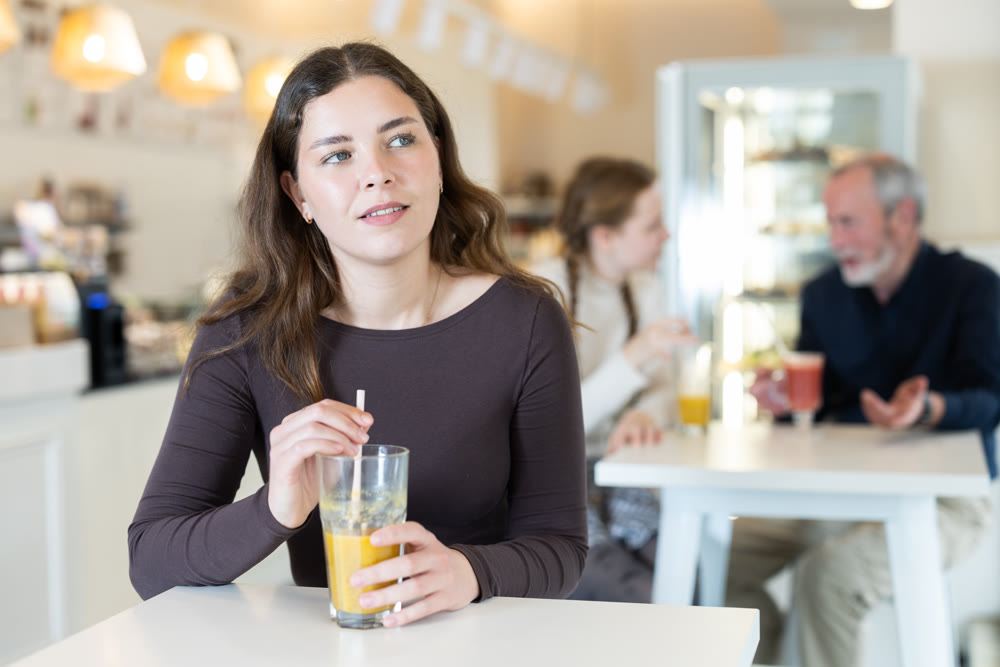 Food court girl visitor sits near table, drink juice in chain cafe shop