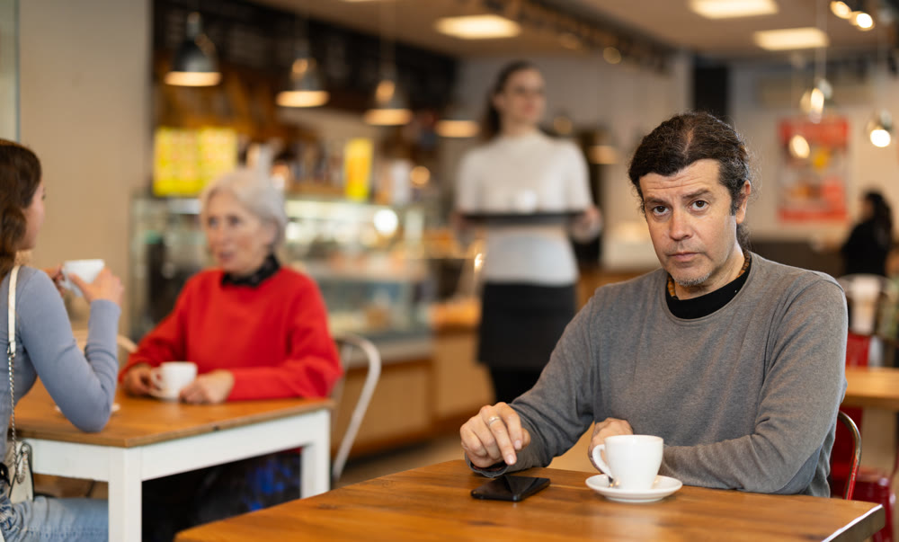 Man drinking coffee and looking at mobile phone screen. Waiting for meeting