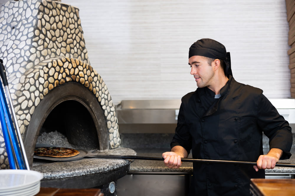 Skilled man chef preparing pizza in restaurant