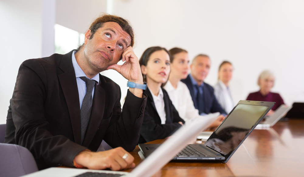 Middle aged white business man yawning at boring meeting