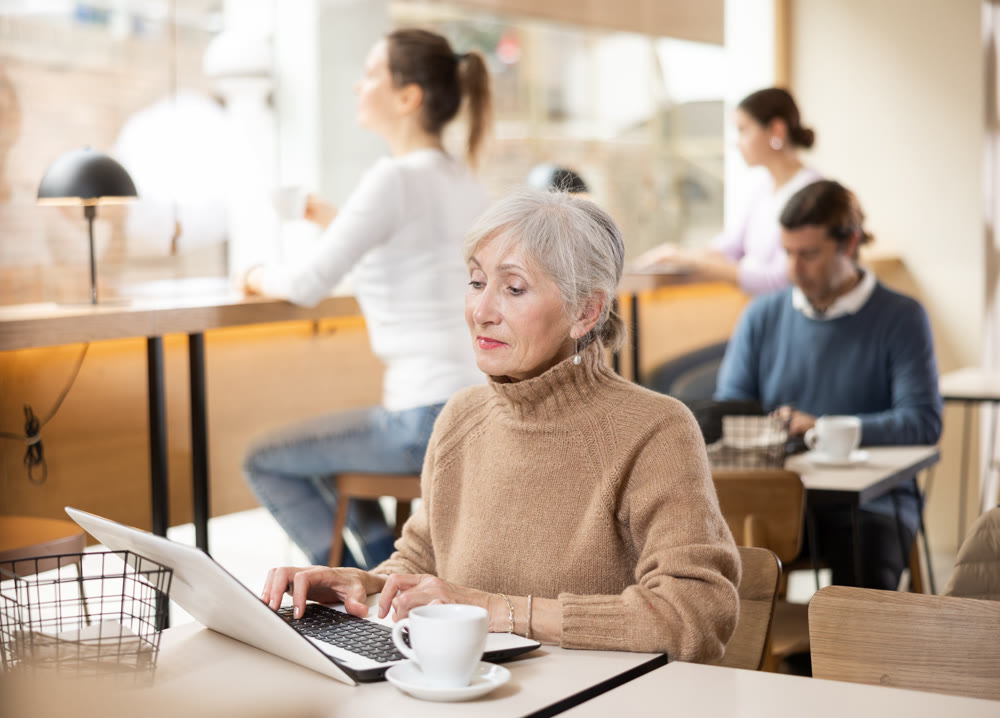 Confident senior female cafe customer enjoying peace and quiet while working on laptop