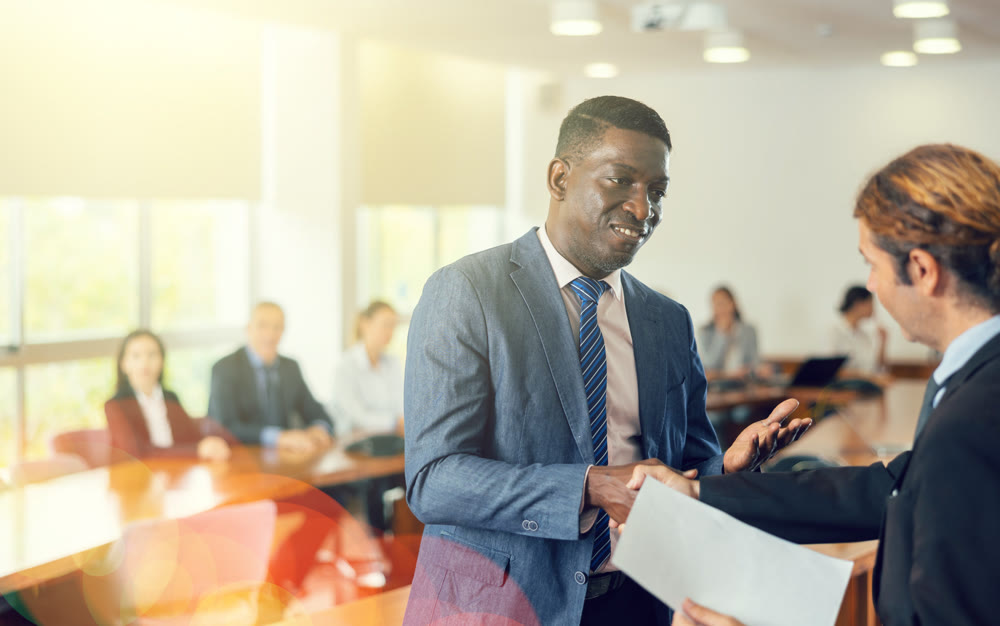 Middle aged african manager welcoming a new white male employee