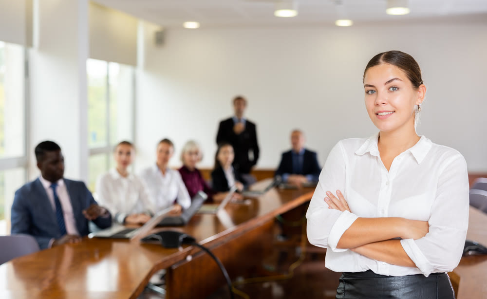 Portrait of successful businesswoman in front of team of businessmen in meeting room