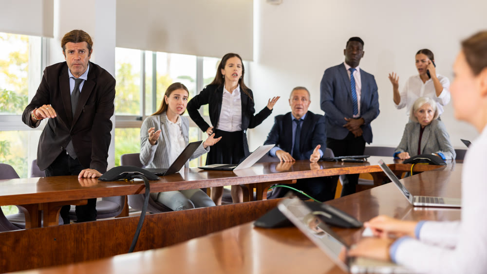 Managers expressing dissatisfaction with teamwork of colleagues at meeting