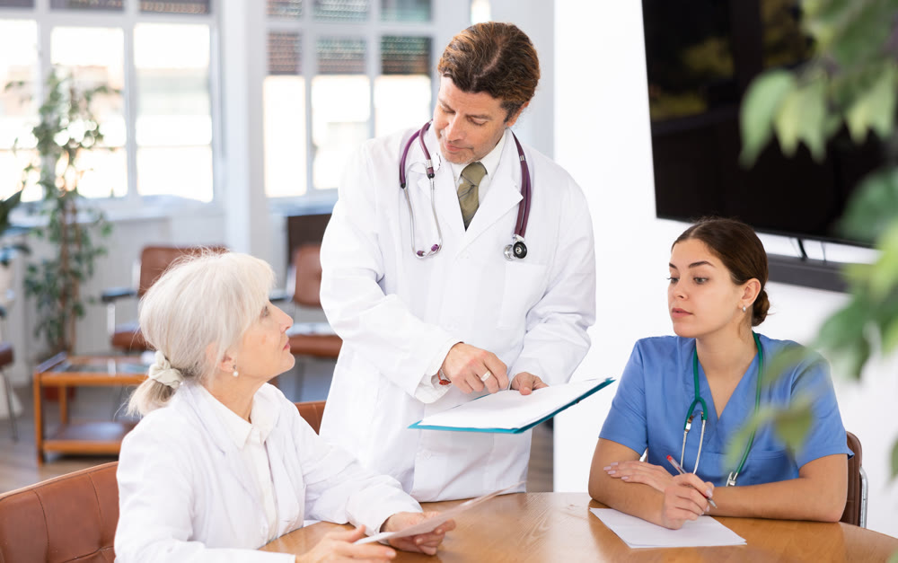 Group of professional doctors sitting at table and discussing diagnosis and treatment of patients during medical council