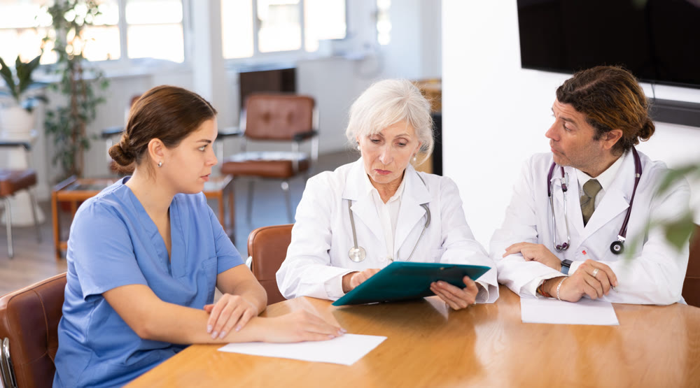 three positive doctors are sitting at table animatedly and actively discussing current work