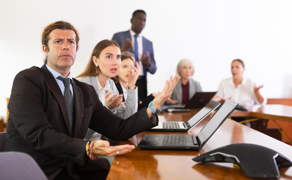 Managers expressing dissatisfaction with teamwork of colleagues at meeting