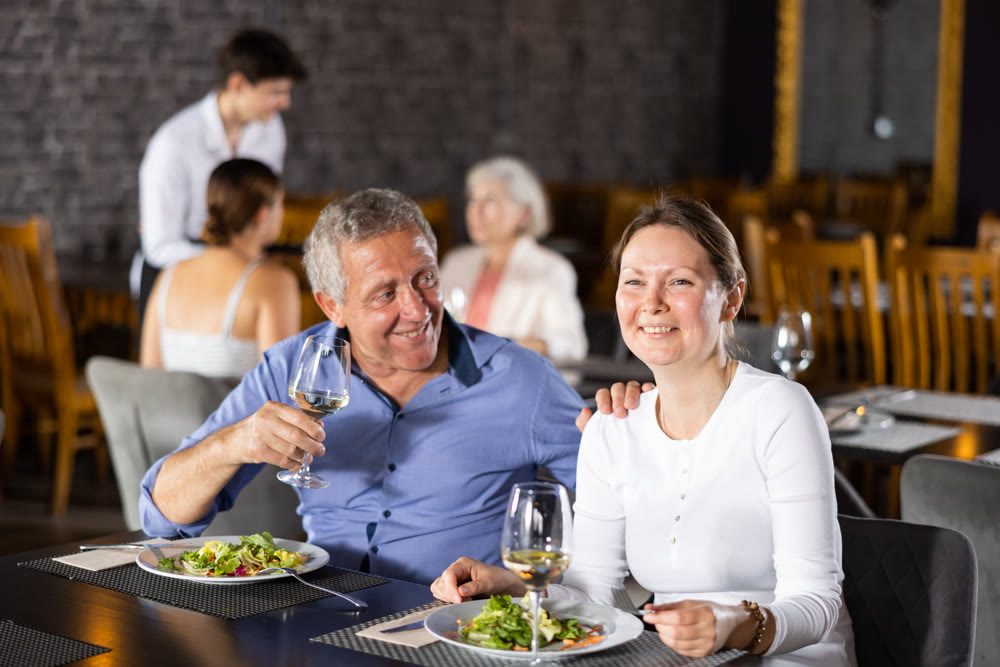 Elderly man resting in restaurant with young female companion