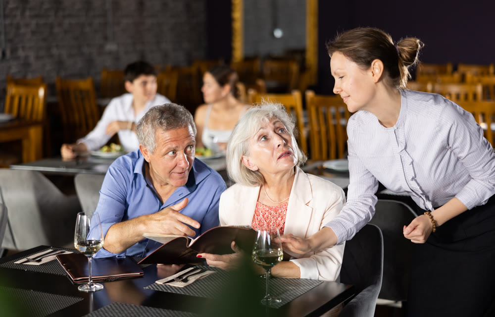 Woman waiter taking order from elderly couple in restaurant