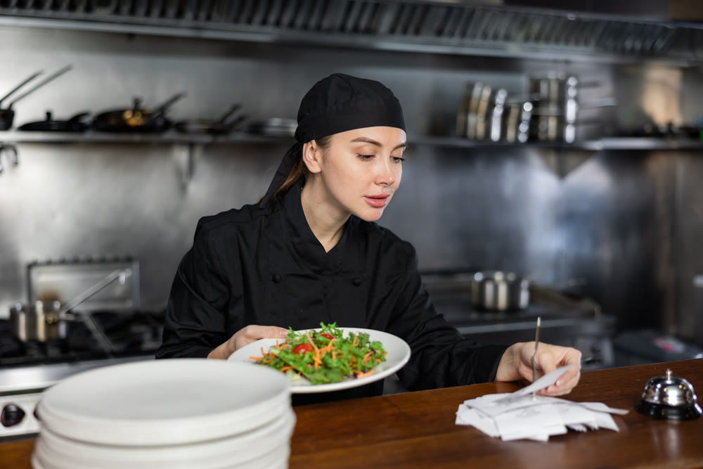 Woman cook checks paid check and cooked dish in kitchen