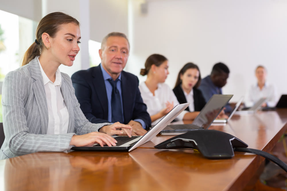 Mature businessman prompts and helps businesswoman during business meeting