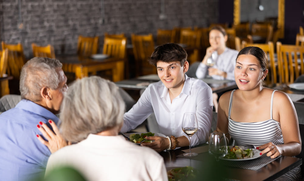 Elderly couple and young couple having dinner in restaurant