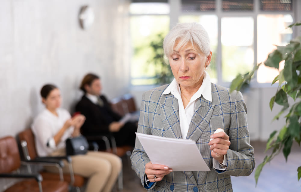 Elderly woman posing with documents in office