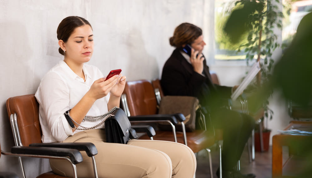 Young girl with phone waiting for job interview in office lobby
