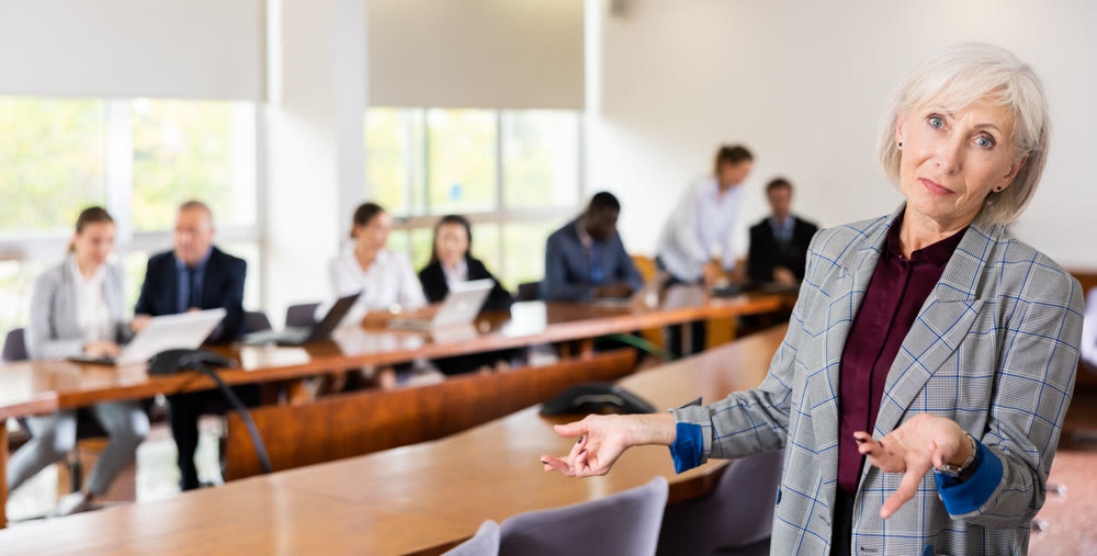 Elegant senior white businesswoman posing with welcoming hand gesture