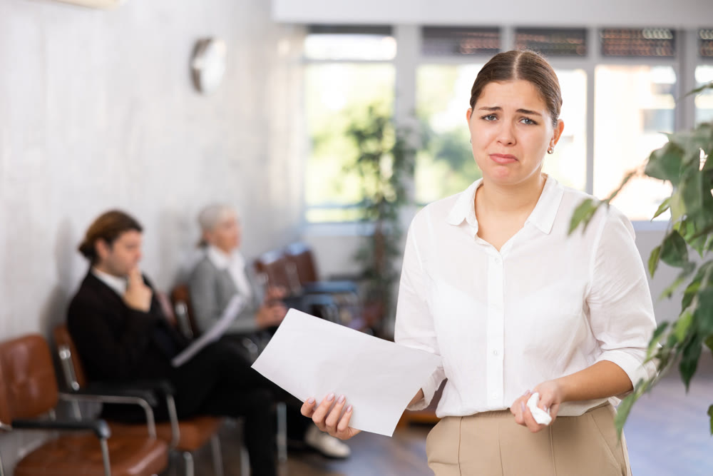 Portrait of upset disappointed female office employee holding paper document in hands