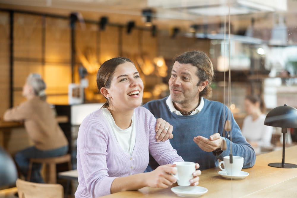 Cheerful man and woman enjoying date in cozy cafe