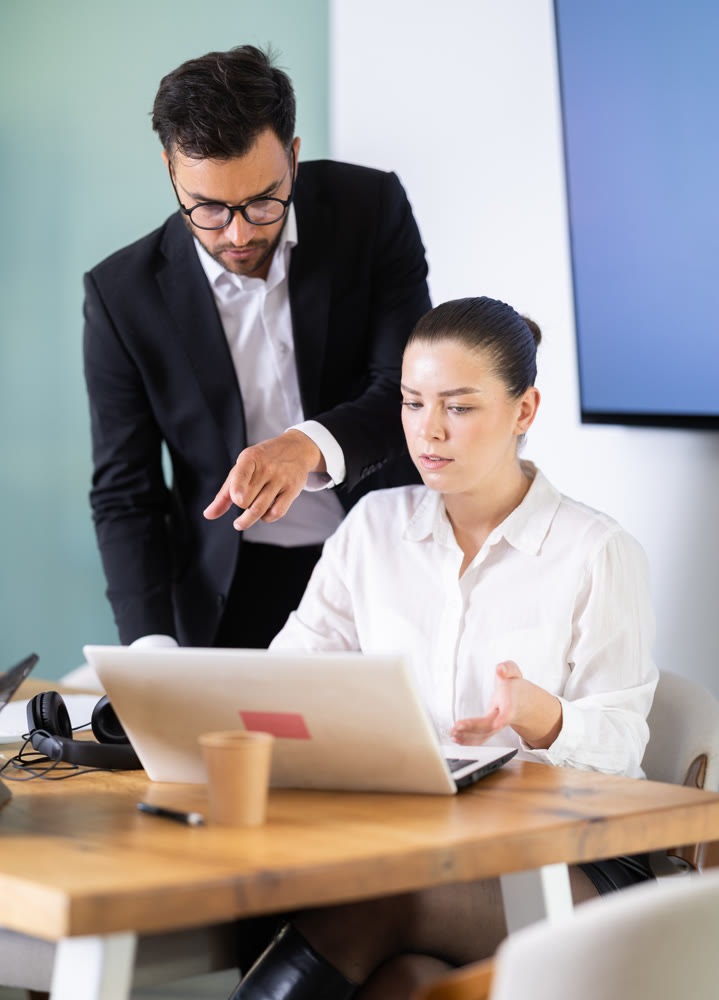 Male manager helping to woman during working at laptop