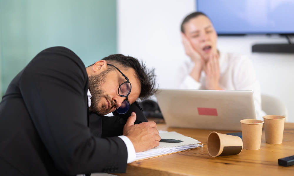 Tired office workers having nap while sitting in workplace