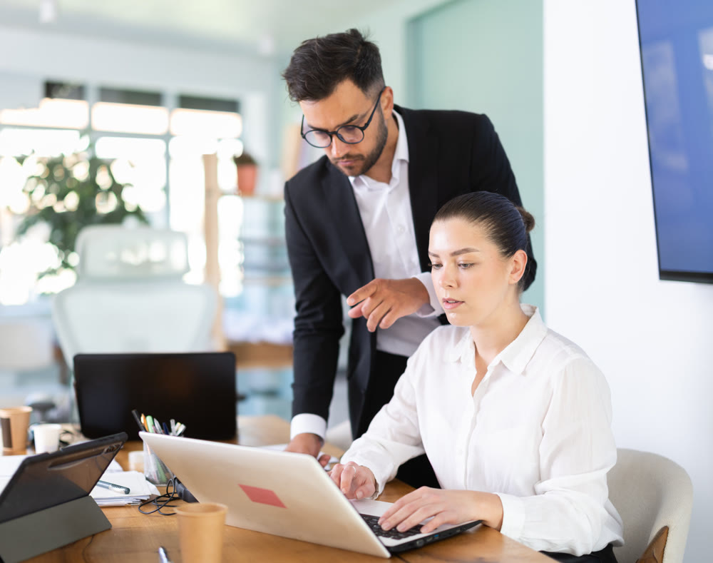 Male manager helping to woman during working at laptop