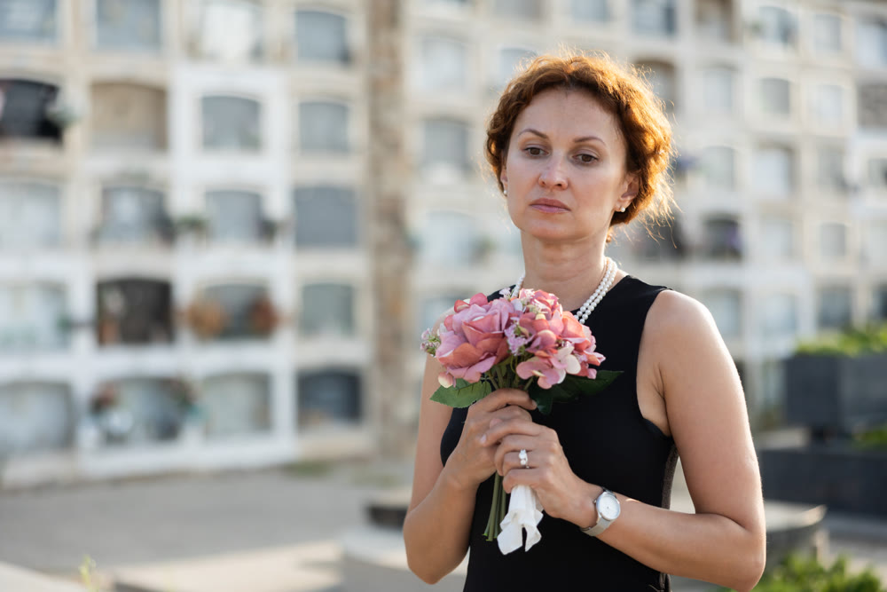 Woman brought flowers to the cemetery and cries over the death of beloved relative