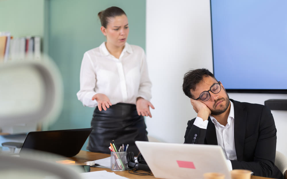 Female boss stands near a sleeping man during work