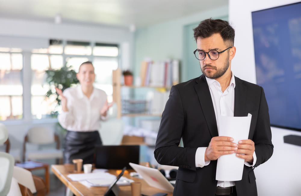 Sad man standing in office, he holding resignation papers