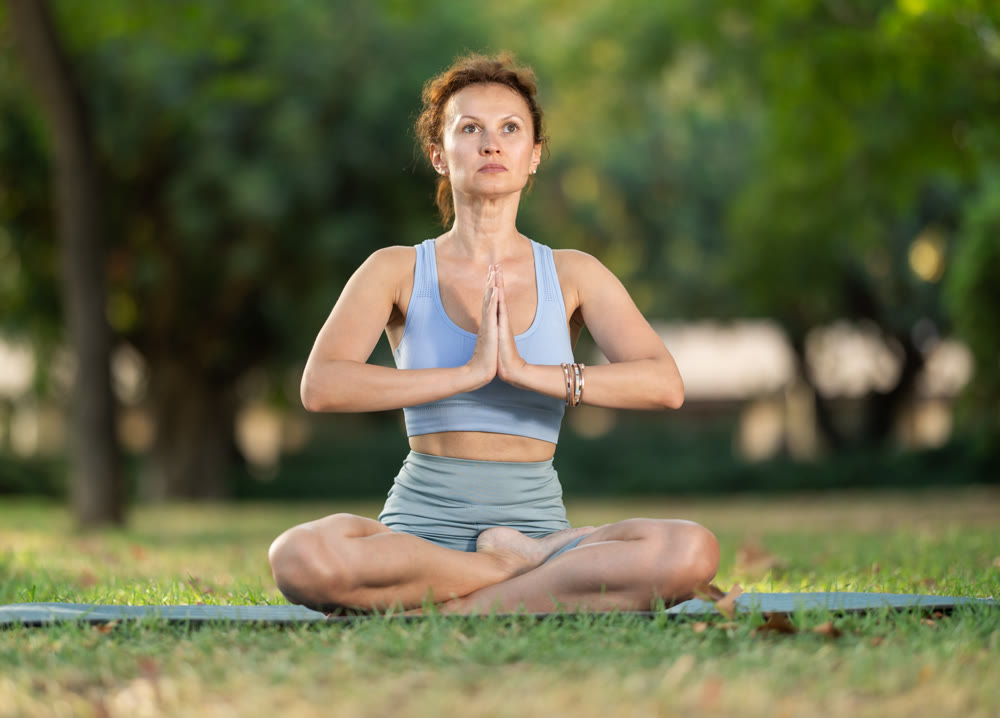 Lotus pose - slim woman doing yoga outdoors in park