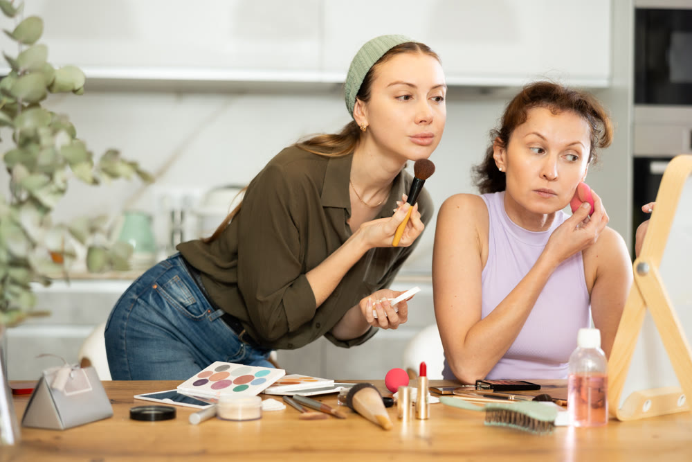 Two women applying makeup to themselves