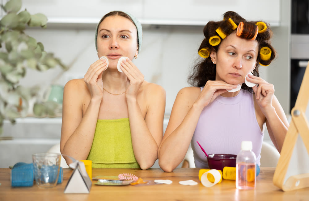 Two women cleanse their face with cotton pads