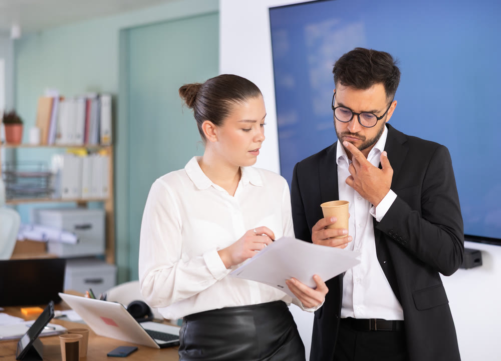 Man and a woman work in an office and look through the documents