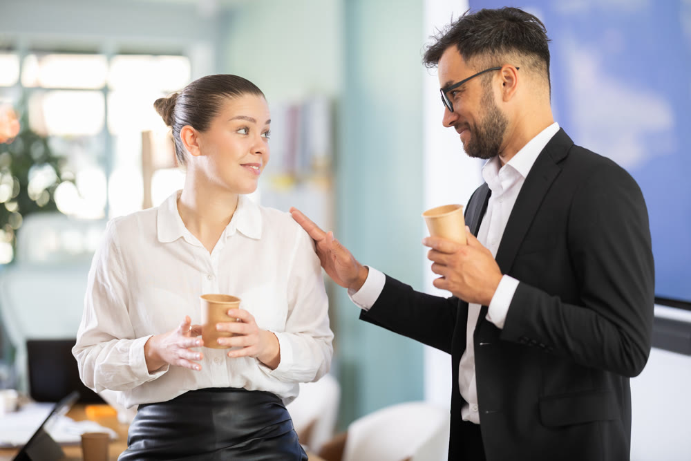 Man and woman talking, laughing and joking with cup of coffee in hands, coffee break time