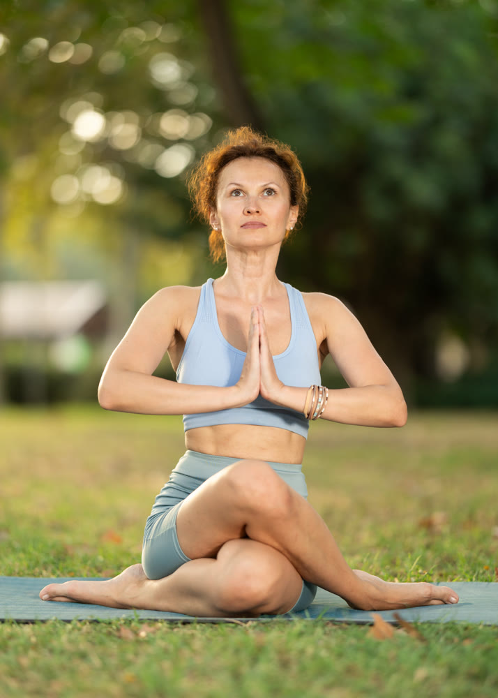 Lotus pose - slim woman doing yoga outdoors in park