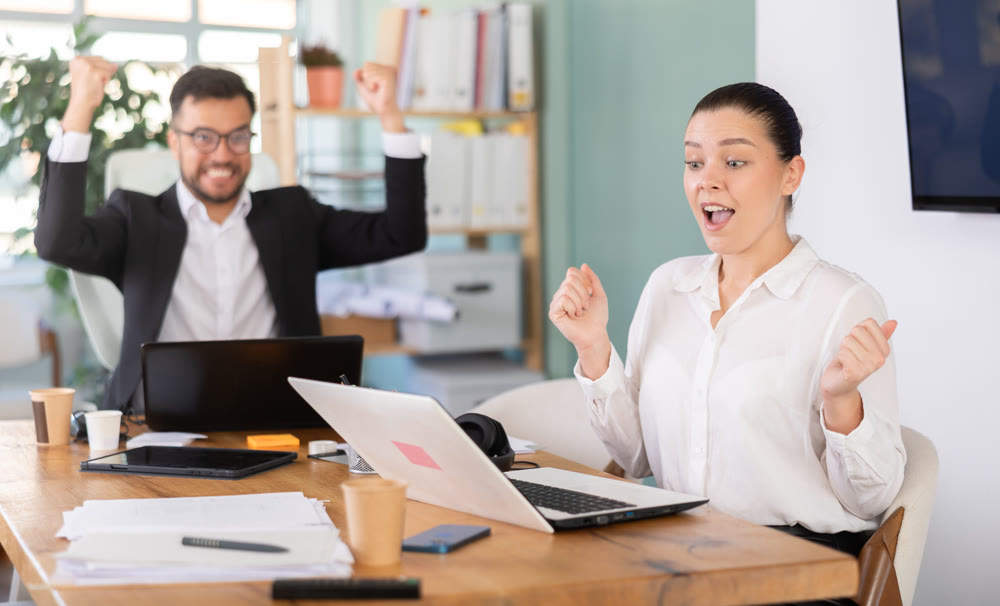 Man and a woman work in an office and are emotionally joy about the success in a new project